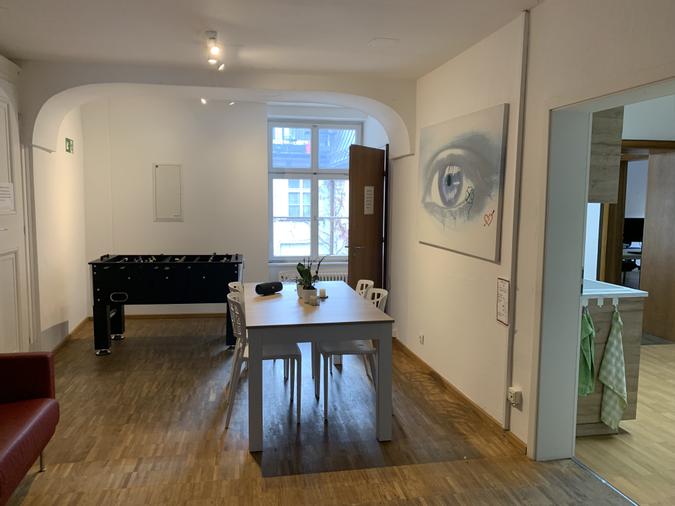 Unser Aufenthaltsraum lädt mit einer gemütlichen Couch, einem ausziehbaren Tisch, Kicker und dem Blick in den Meister-Eder-Hinterhof zum Entspannen und Verweilen ein.