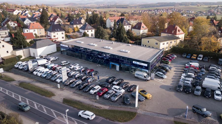 Unser FordStore auf der gegenüberliegenden Straßenseite mit Fläche für Lagerfahrzeuge und Direktannahme
