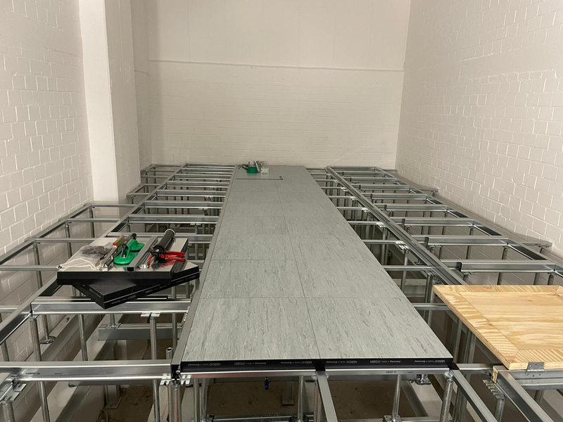 Schaltwartenboden mit zum Teil verlegten Doppelbodenplatten und Luke